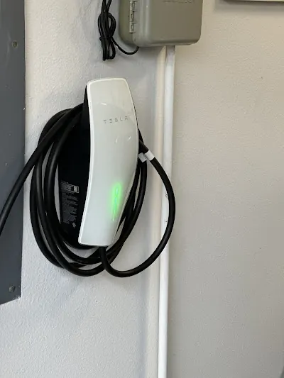 White wall-mounted EV charger with its cable wrapped