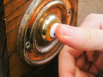 Finger pressing a wired doorbell button