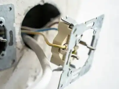 Outlet pulled out of the wall showing its wiring