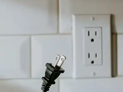 Outlet on a tiled backsplash with a cord plugged in